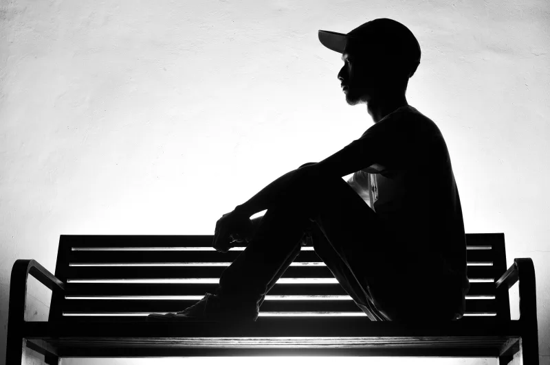 男性在低光源環境中低頭思考自身用藥與健康狀況